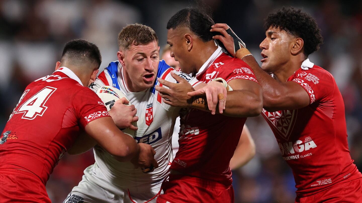 Defensores de Tonga de rojo rodean al portador del balón de Inglaterra durante el partido del Mundial masculino de Rugby League de 2026 en el HBF Stadium, Perth, el 17 de octubre de 2026