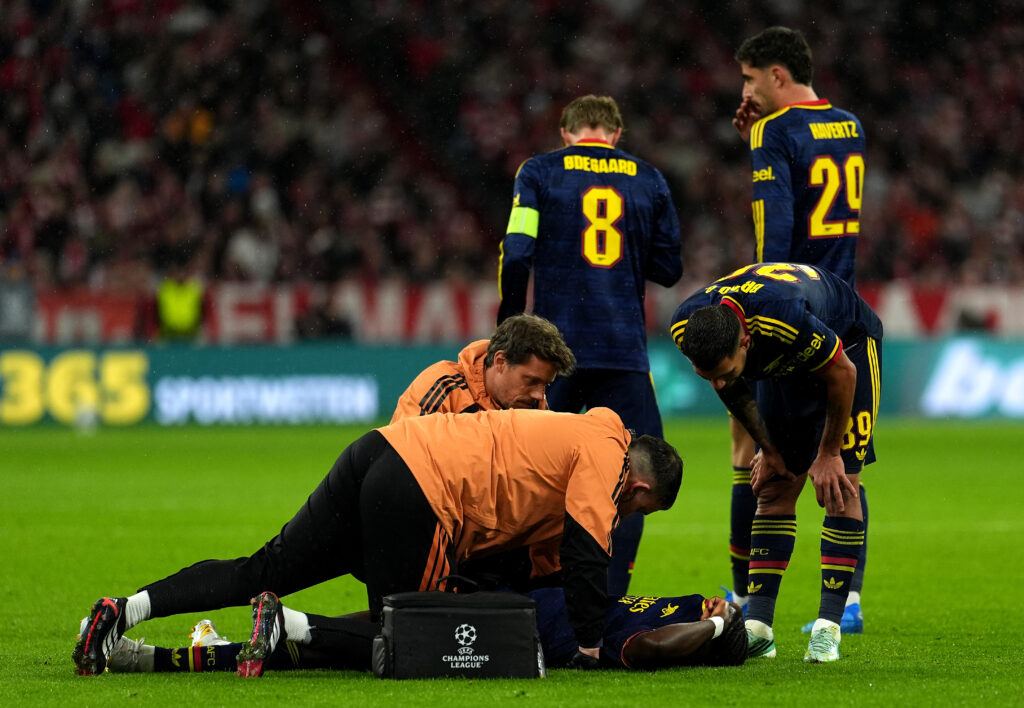 Bukayo Saka of Arsenal receives medical attention on the pitch after sustaining a quadriceps injury during the Champions League match against Bayern Munich at the Allianz Arena on October 21, 2026