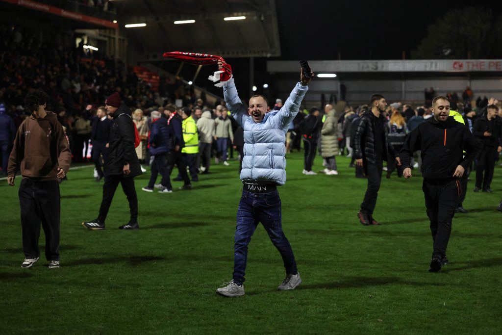 Fleetwood fans celebrate on the pitch at Highbury Stadium after the penalty shootout win over Arsenal on 27 October 2026 (AFP photo via Vanguard).